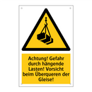 Achtung! Gefahr durch hängende Lasten! Vorsicht beim Überqueren der Gleise!